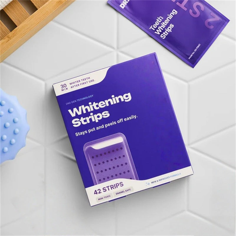 Box of teeth whitening strips with purple packaging on a white tiled surface
